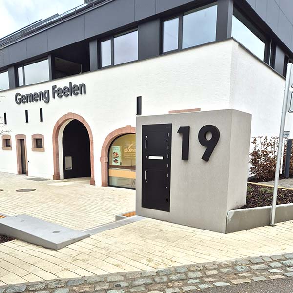 Flächenbündiger Einbau eines Paketkastens in freistehenden Betonblock vor einem Rathaus