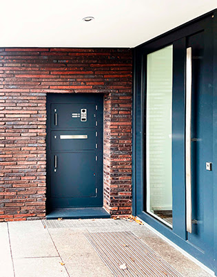 Paketkasten mit Tuersprechanlage integriert in Backsteinhauswand - von vorne.